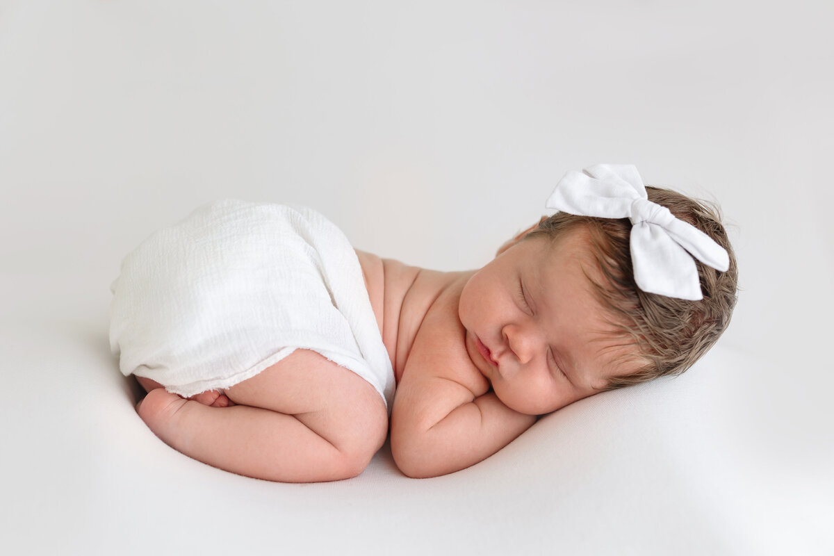 baby girl laying with bow on head