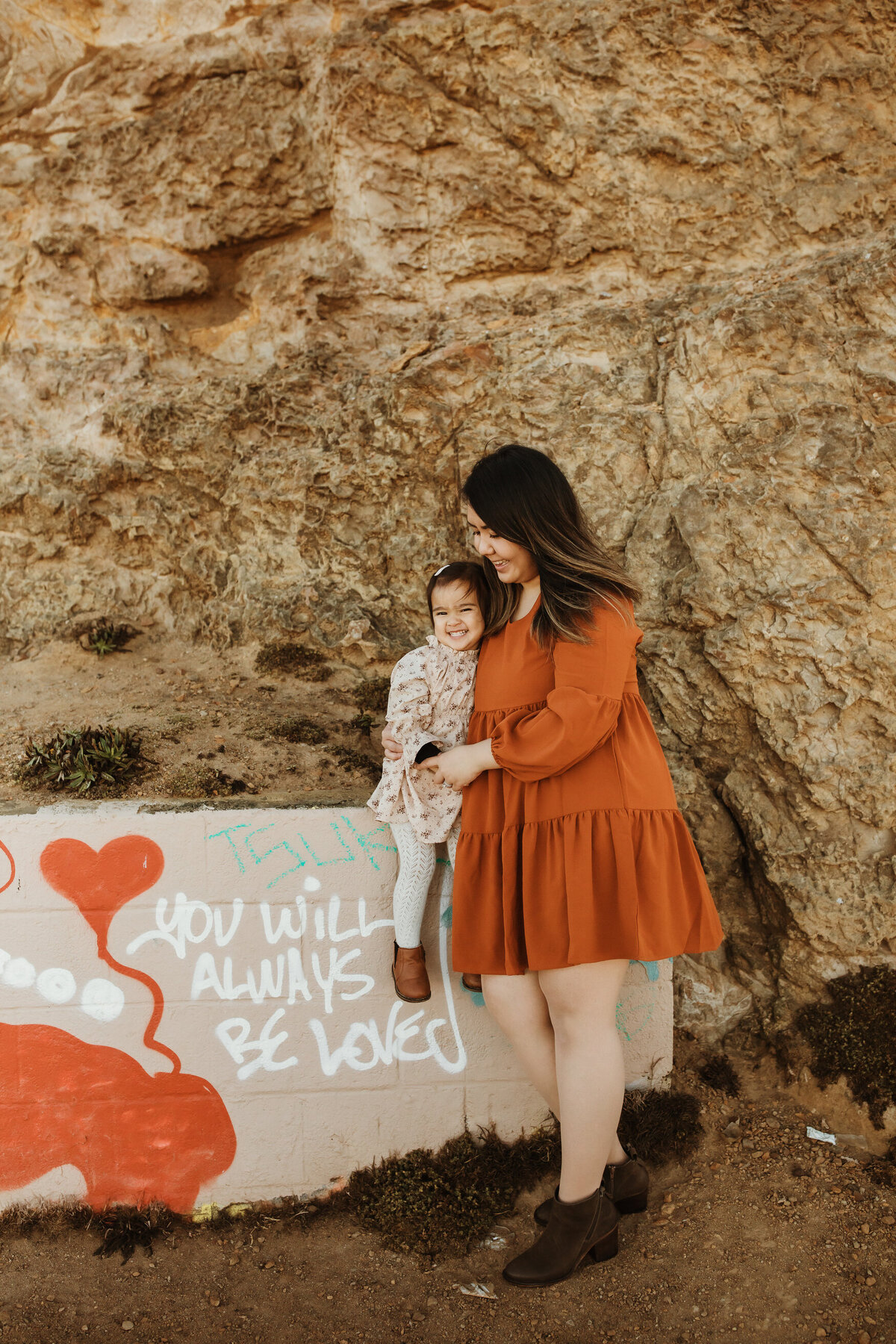 Mother and daughter in front of grafitti that says 'you will always be loved' at Lands End in San Francisco