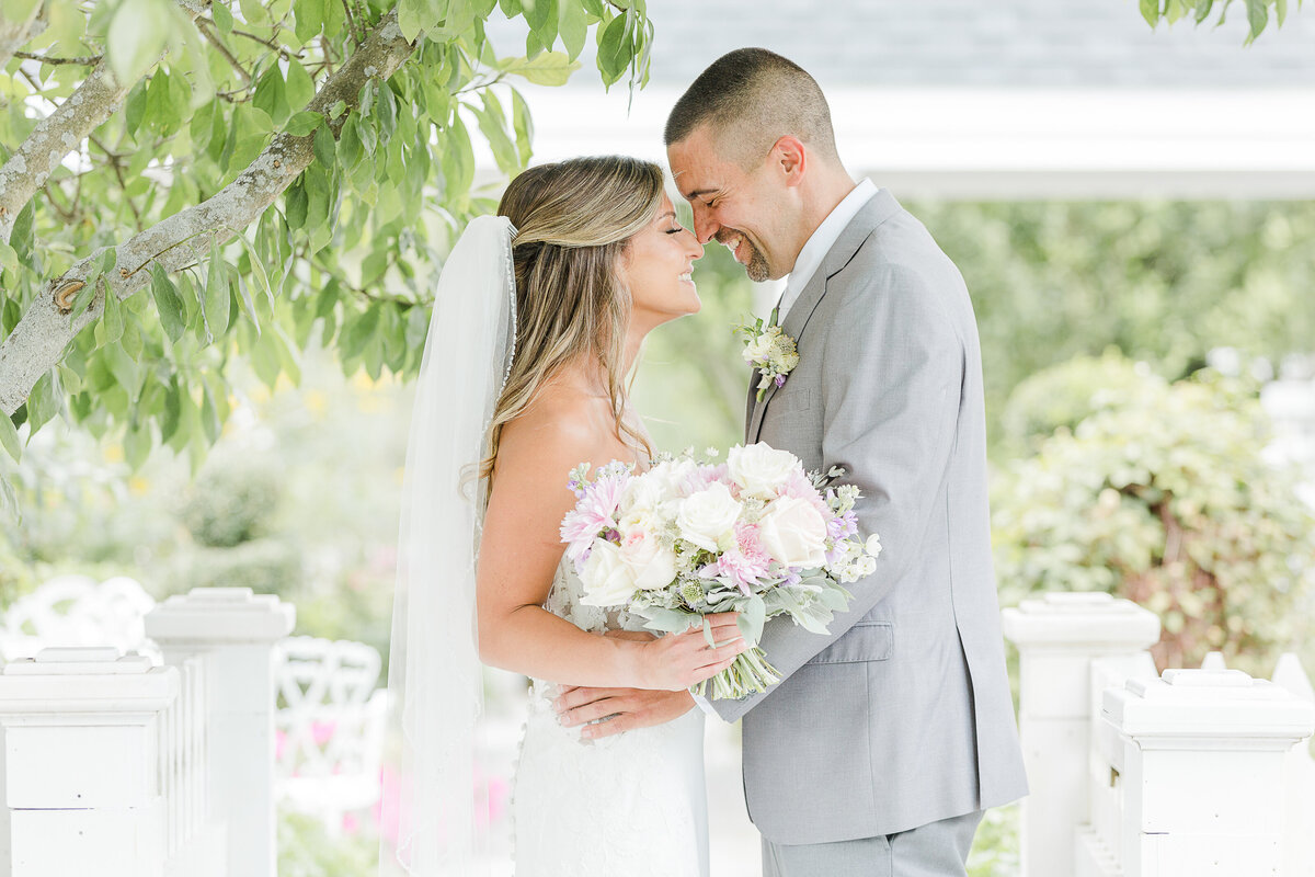 Bride and groom touch noses and smile for an intimate wedding day portrait. Captured by best Massachusetts wedding photographer Lia Rose Weddings.