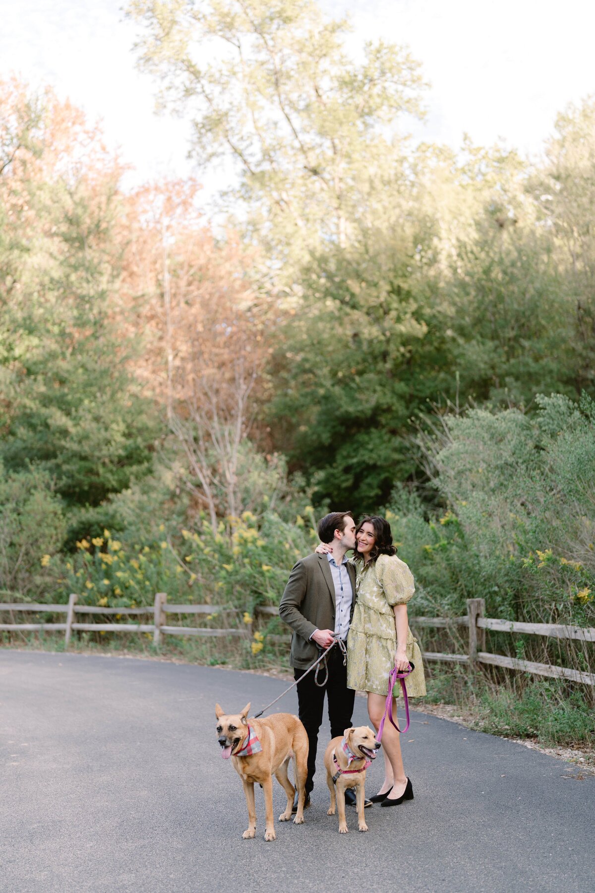 Couple embracing while holding two dogs on leashes