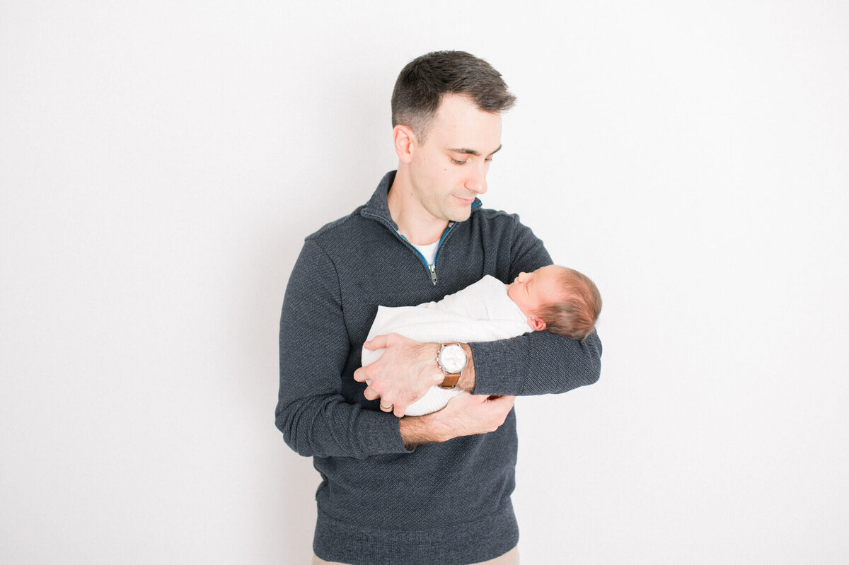 Dads portrait with newborn . Light and bright studio photography.