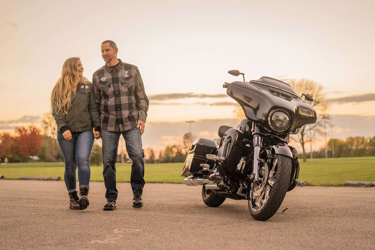 engaged couple walking together next to their harley