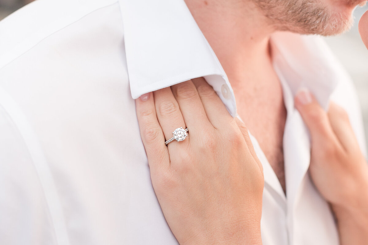 hands holsing lapel with engagement ring showing