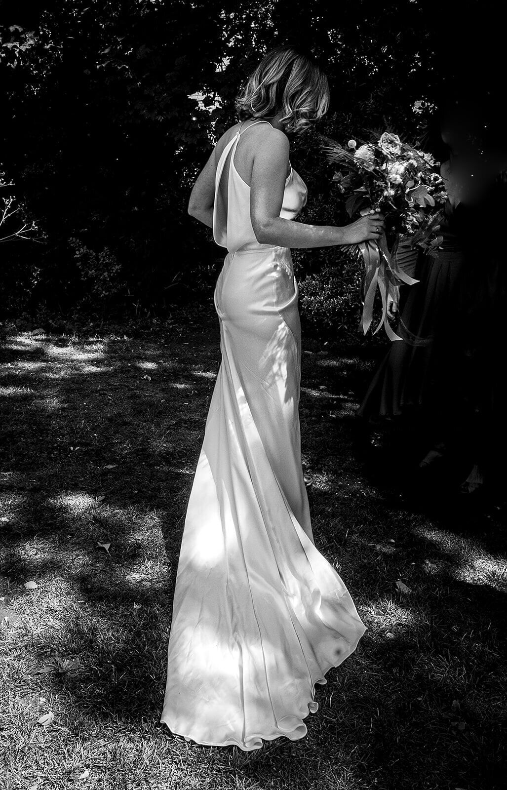 Back shot of bride holding bouquet backless dress