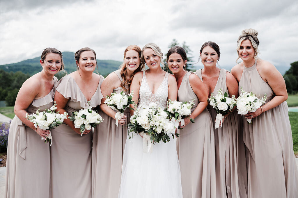 Bride and bridesmaids posing for photos with mountain backdrop