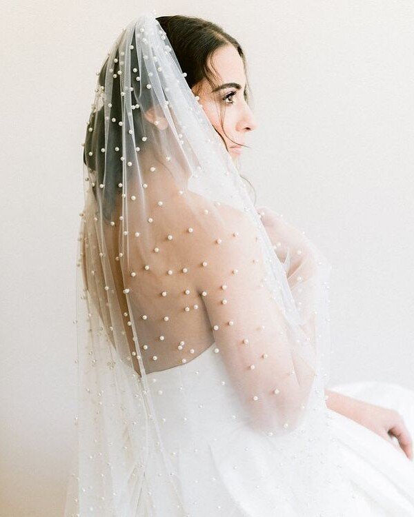 The Pearl Veil is a chapel-length veil made in a pearl covered tulle that has been gathered on one edge onto a comb.