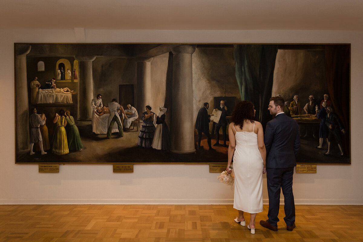 Just Married photo session couple stands in front of large mural at the International Museum of Surgical Science.