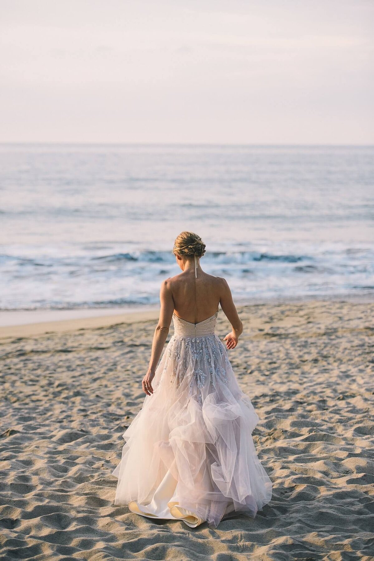 Bride in blush dress walking towards ocean in Mexico Sayulita wedding