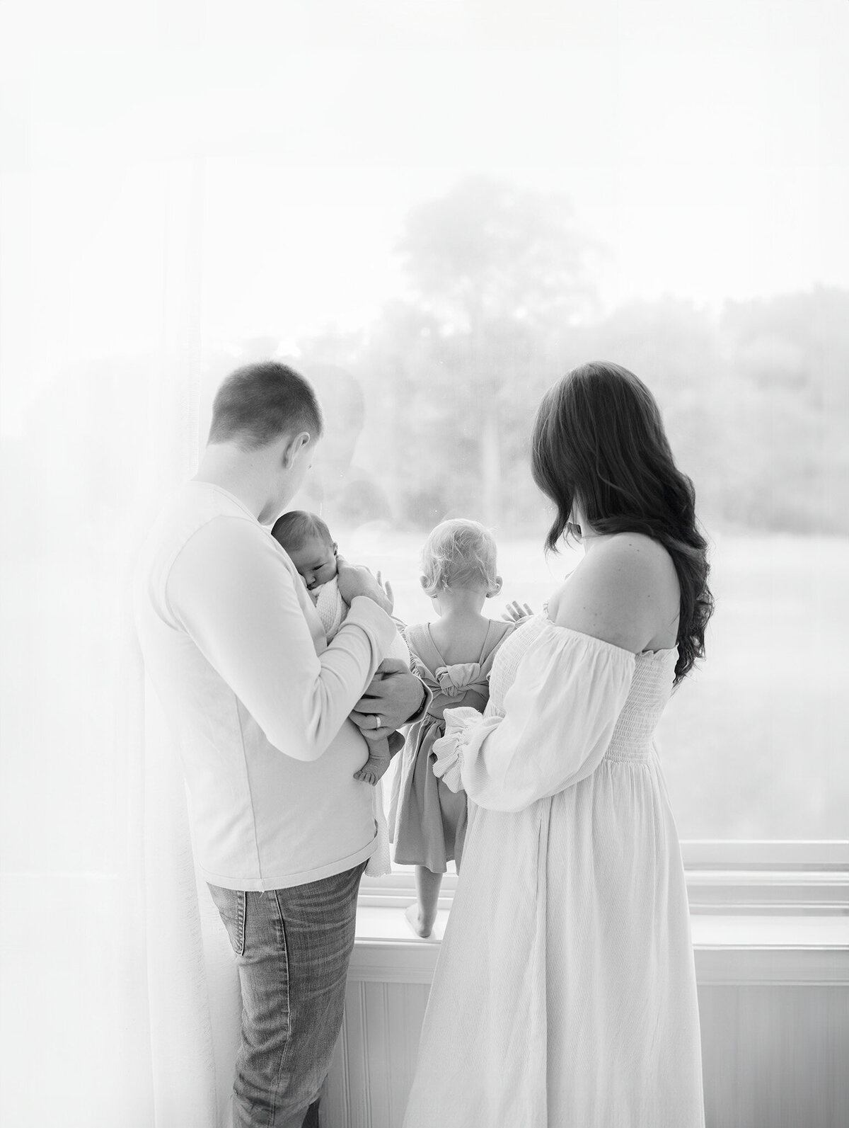 photograph from behind of family of four during boston newborn photoshoot