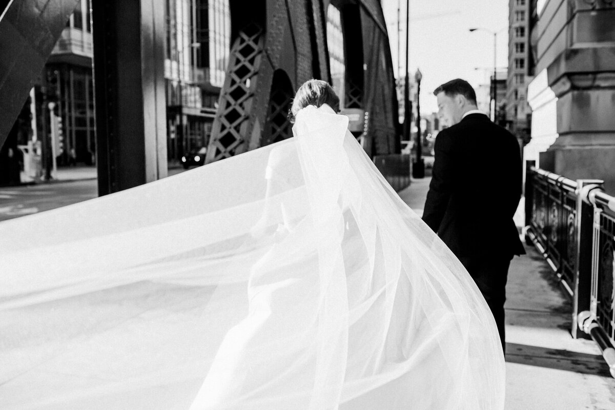 A black and white photo of newlyweds walking across the LaSalle Street Bridge in Chicago