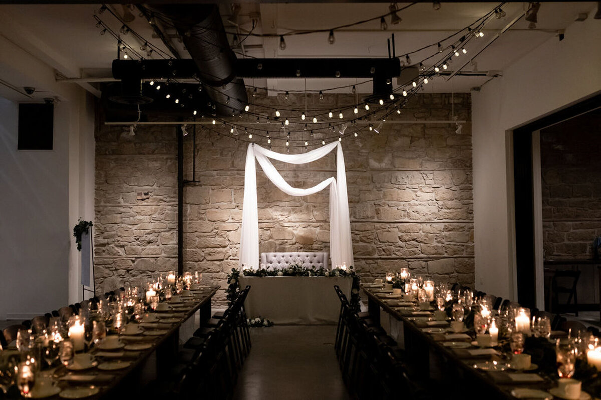 Moody and elegant indoor ceremony at The Pioneer, a historical industrial wedding venue in Calgary, featured on the Brontë Bride Vendor Guide.
