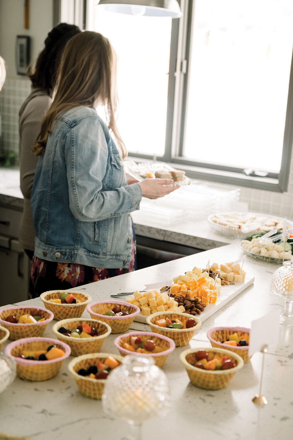 Colorful sugar crystal-rimmed waffle fruit cups filled with fresh, vibrant fruits, served at a pink and yellow girl baby shower.