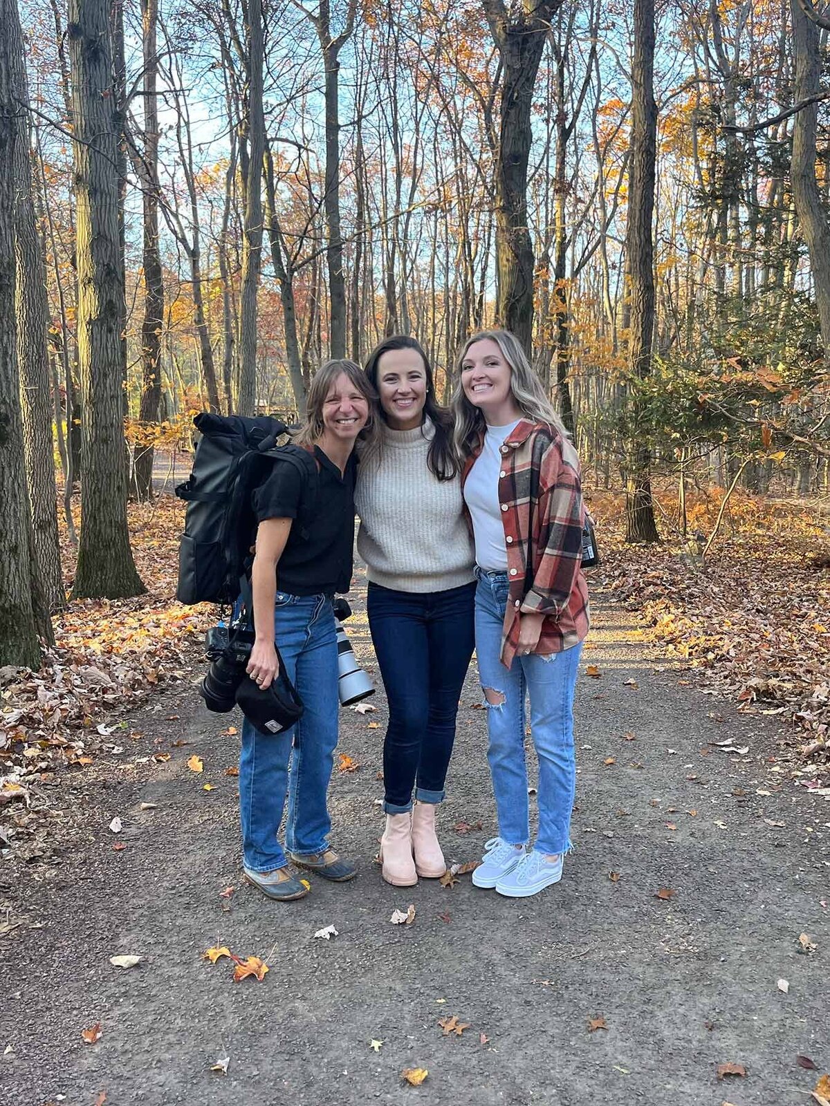 Aimee , an elopement photographer stands in the woods with a couple she just photographed in Pennsylvania