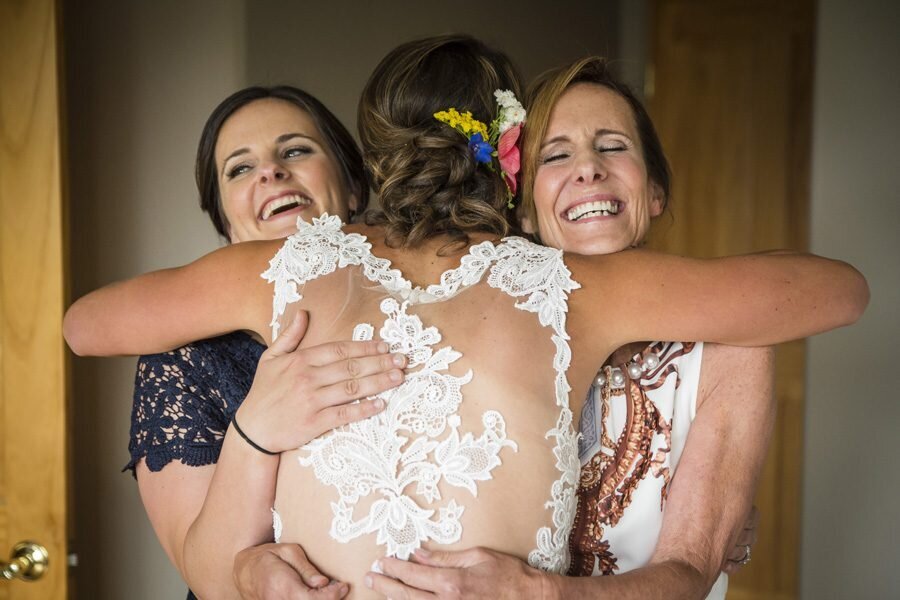 A candid moment of a bride hugging her mom and sister.