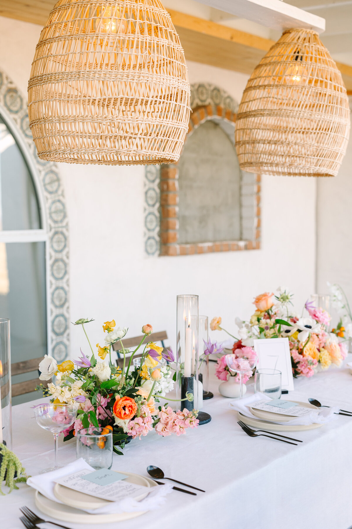 boho wedding reception tablescape with colorful bouquets and woven basket light fixtures.