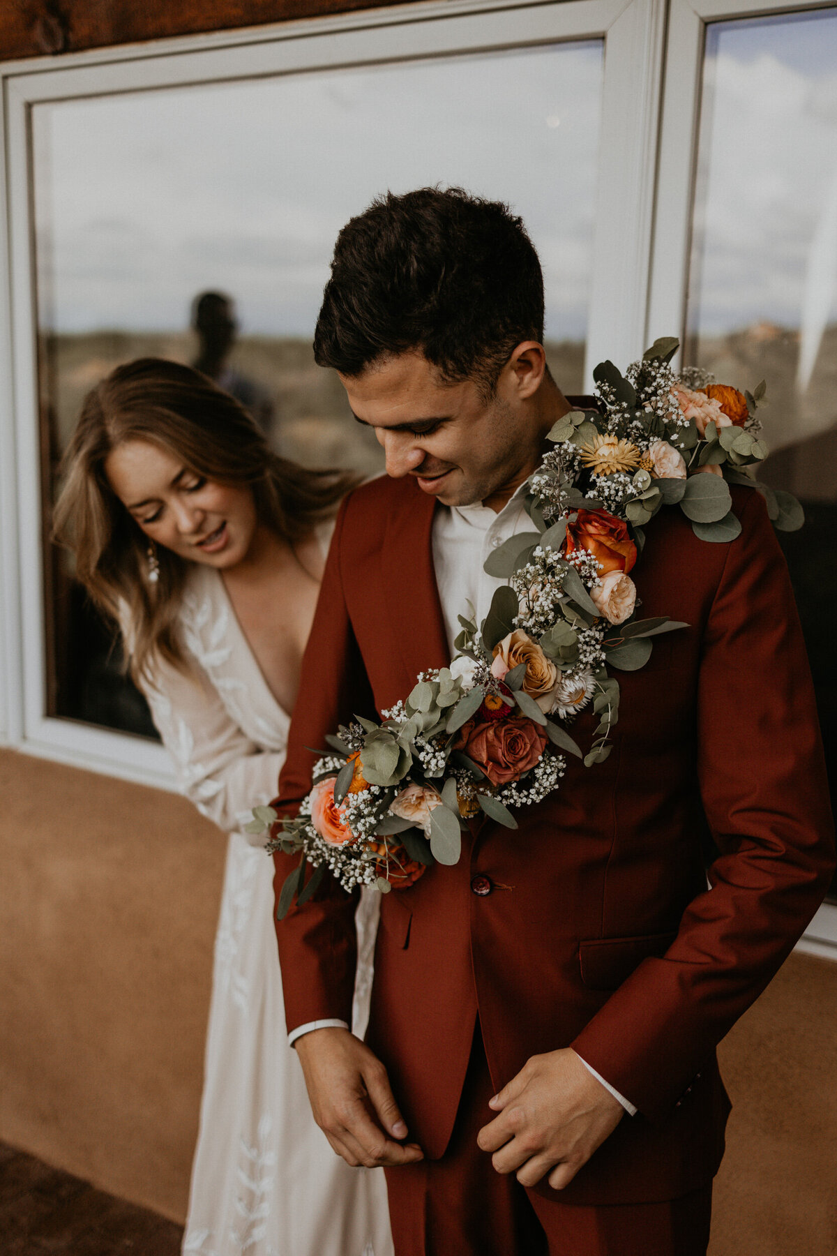 bride putting floral sash on male bridesmaid