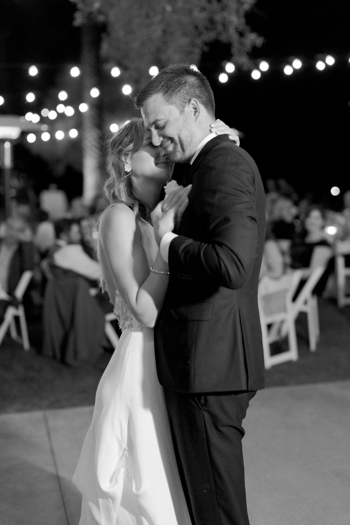 Bride lays fervently on the shoulders of her husband as they dance to their wedding beat.