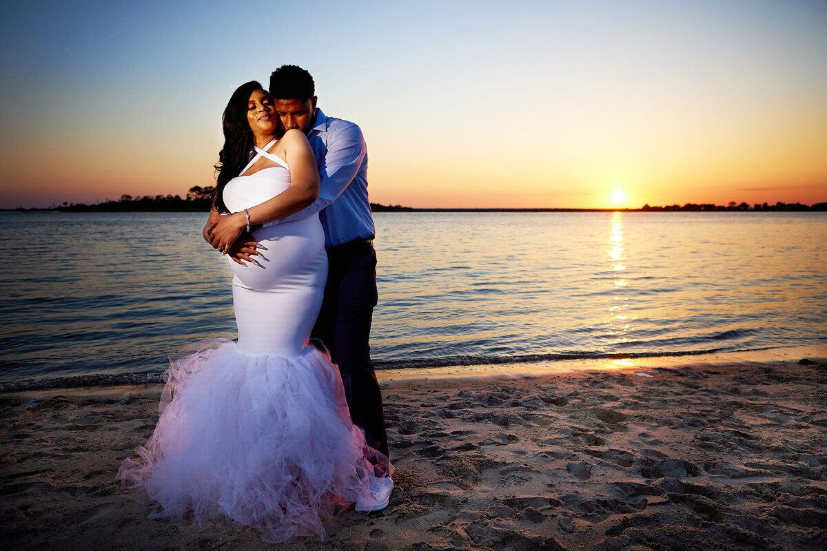 New parents bride and groom celebrating maternity and wedding at Tybee Island sunset on the beach