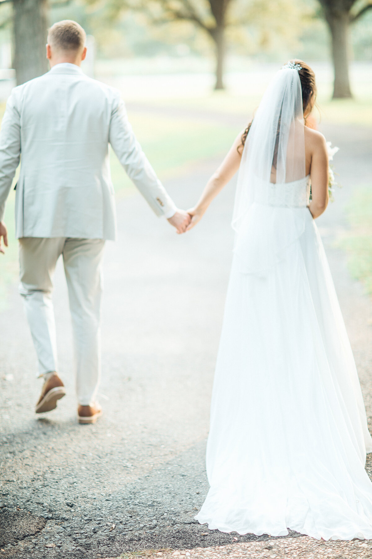 Wedding Photograph Of Bride And Groom Holding Their Hands While Walking