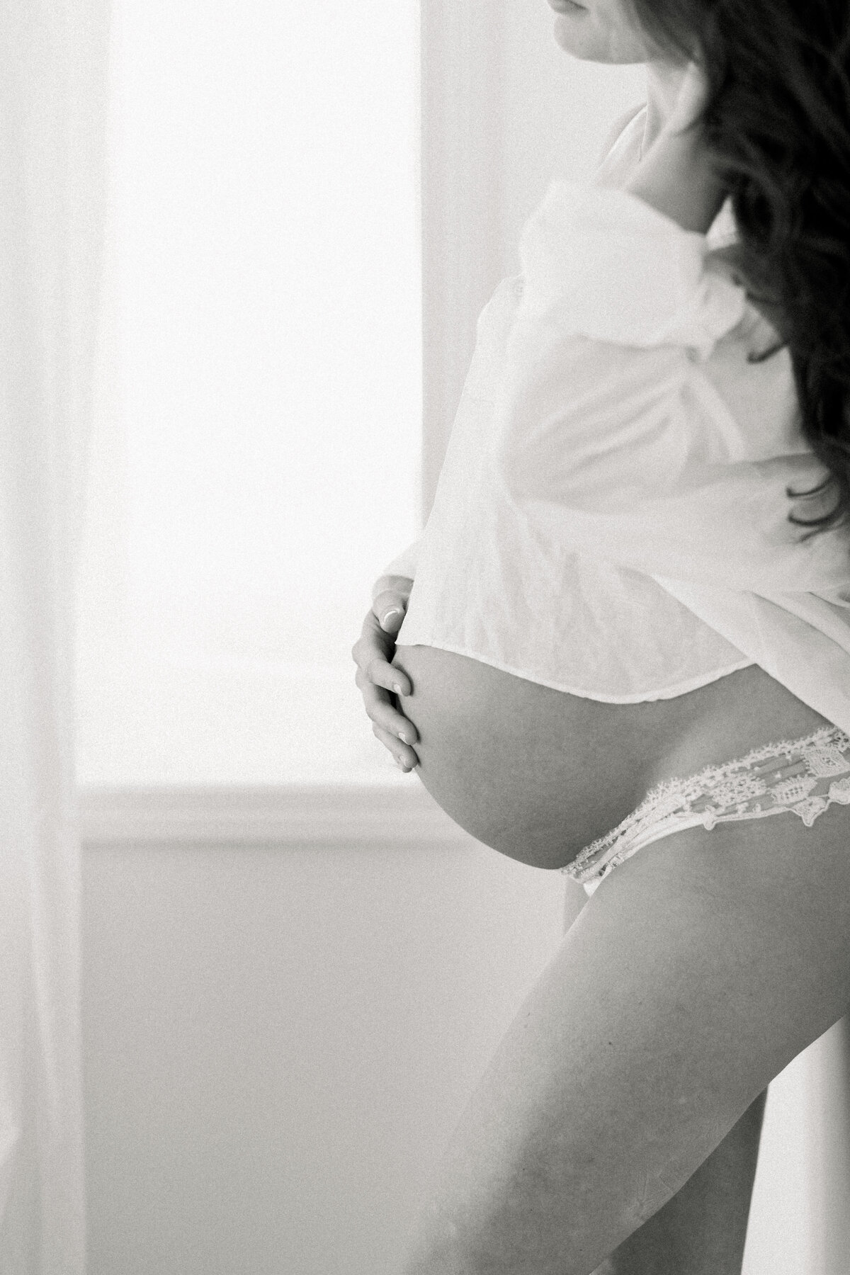 Black and white image of woman holding pregnant belly