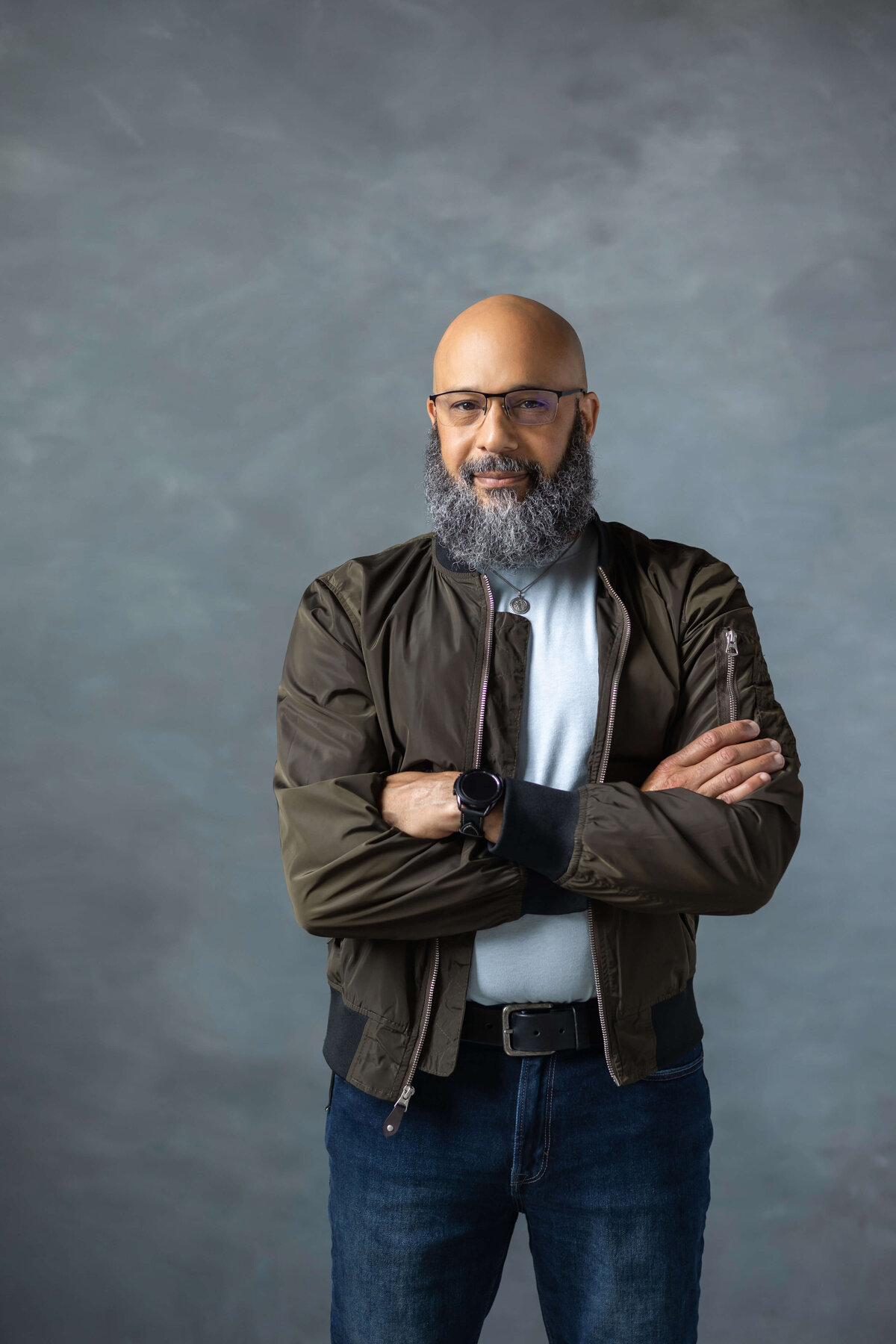 black man in jacket with arms crossed and serious expression