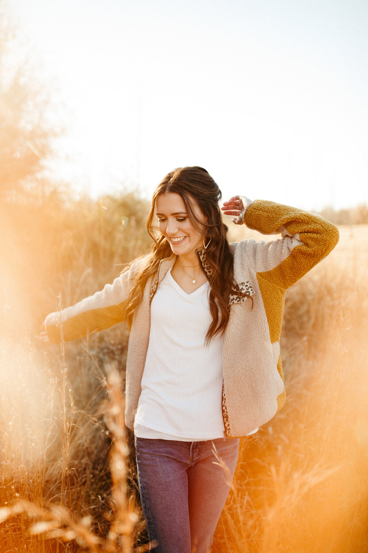 High school senior twirling in a field with tall grass and golden light surrounding her