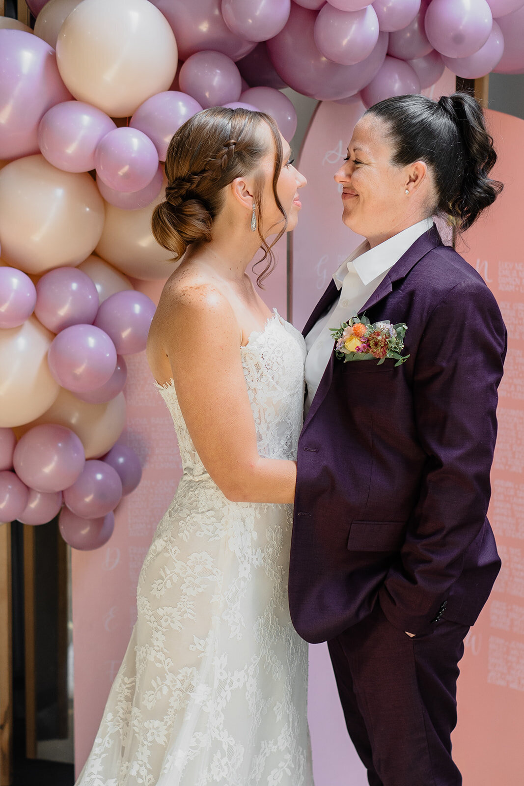 couple staring at each other in front of a balloon garland