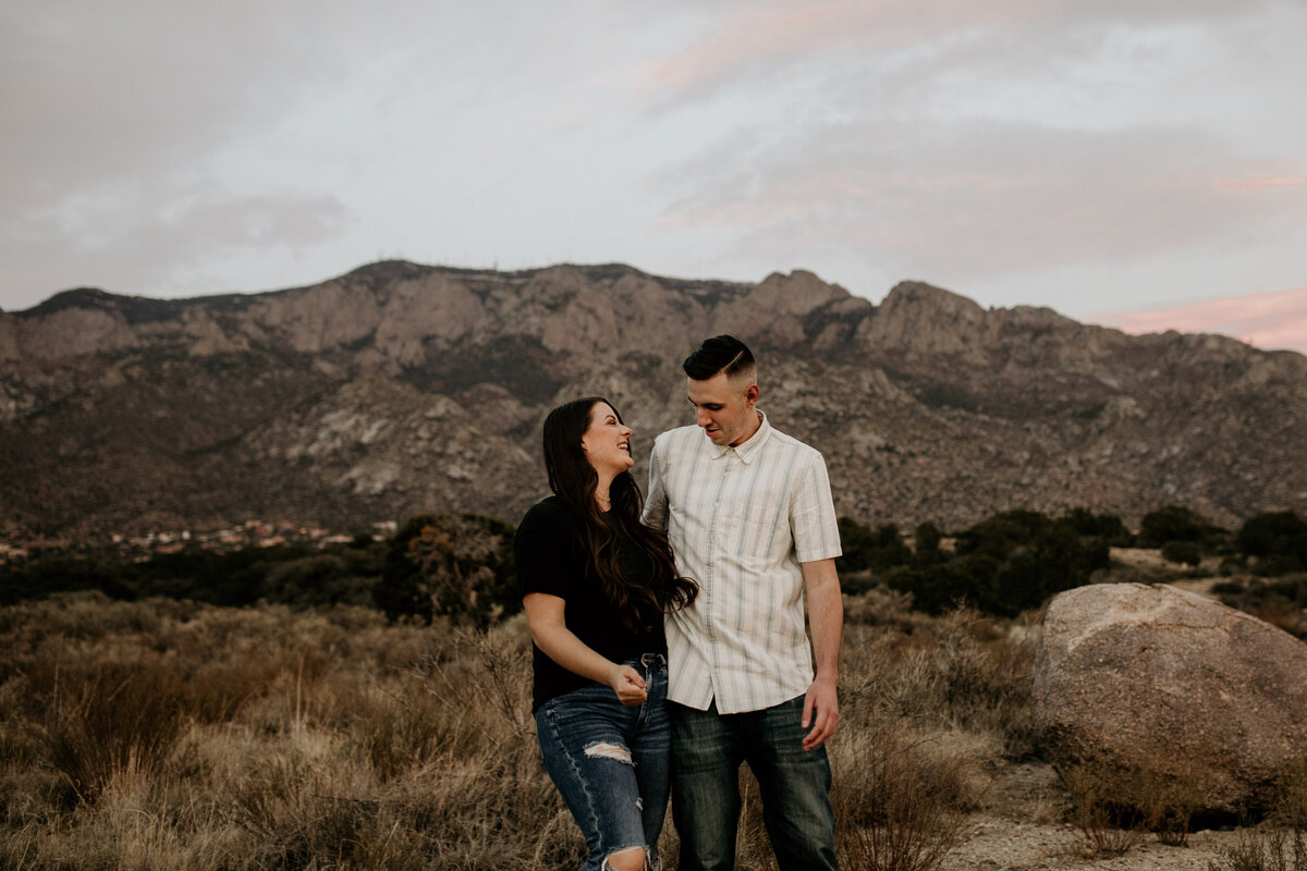 engaged couple laughing and holding each other in front of a mountain
