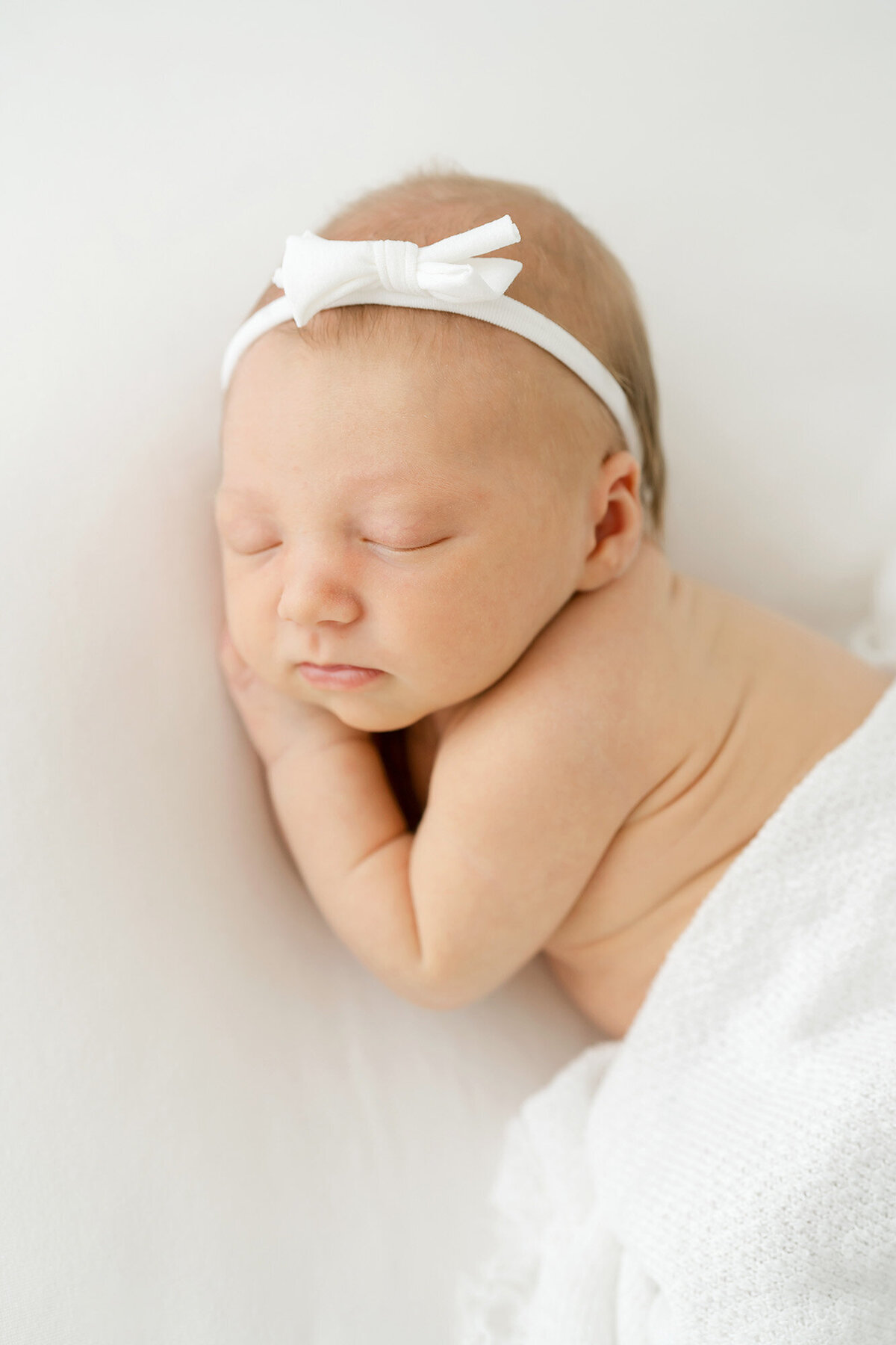 newborn baby girl wears white hair bow from Julie Brock Photography in Louisville KY