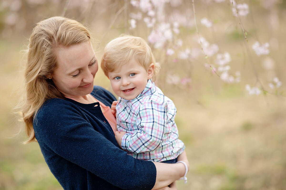 Family session of little boy and his mother outside near flowers