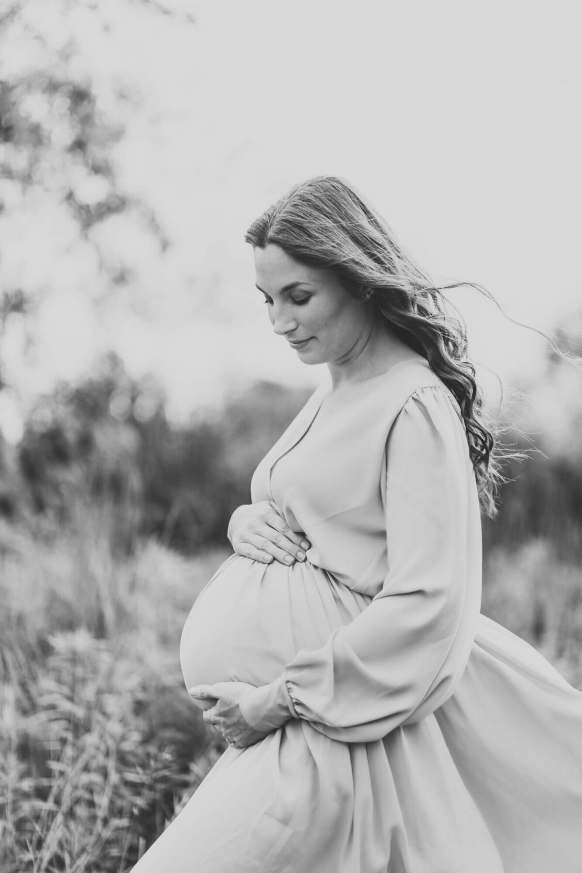 black and white image of mother holding her pregnant belly.