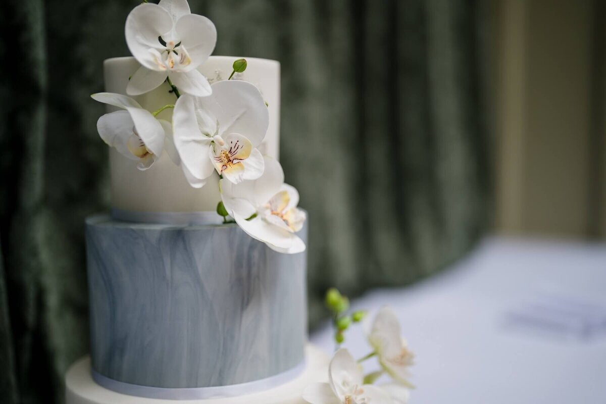 A close up of a three tier wedding  cake with orchid sugar flowers