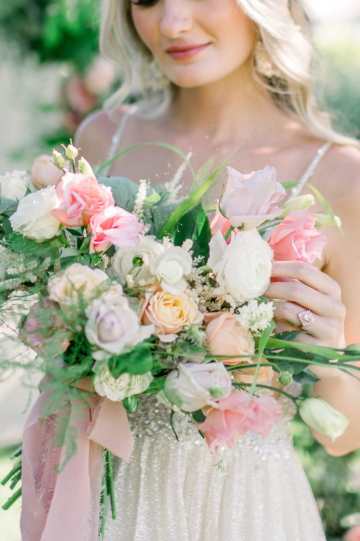 close up photo of bridal bouquet with pink white and peach flowers with greenery by arkansas wedding photographer