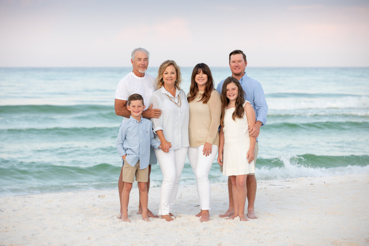 A family smiling while on a white sand beach