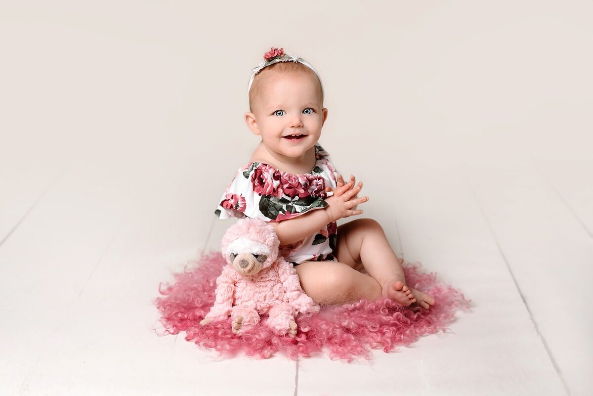 Baby girl laughing in pink and white floral romper.