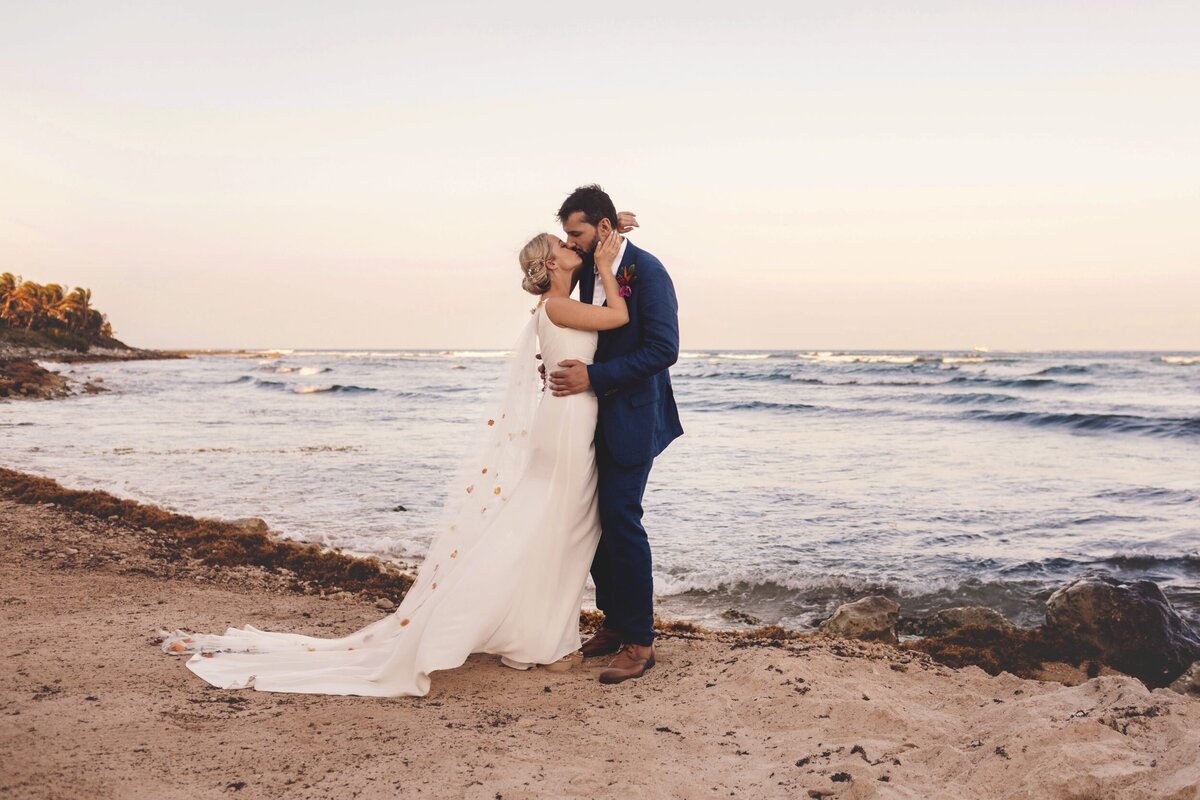 Birde and groom kissing on beach at wedding in Riviera maya