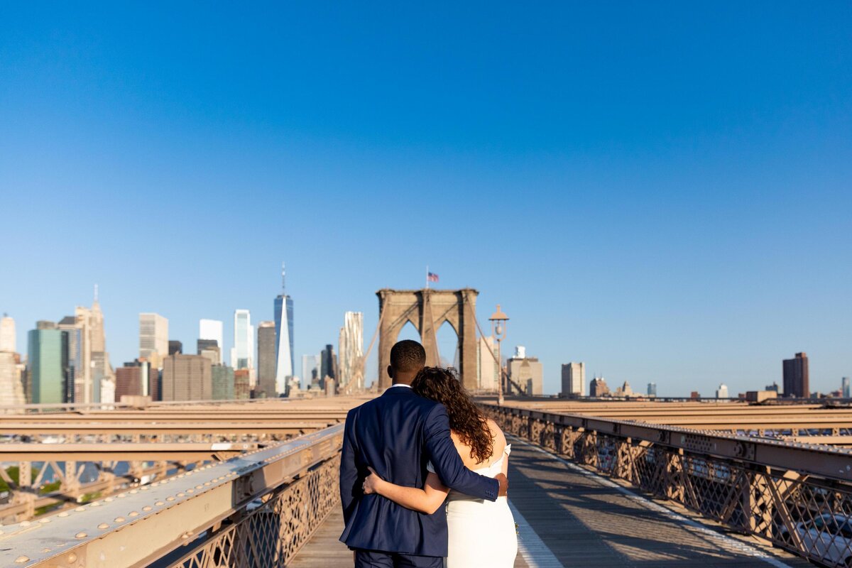 A couple with their arms around each other looking out over a city skyline.