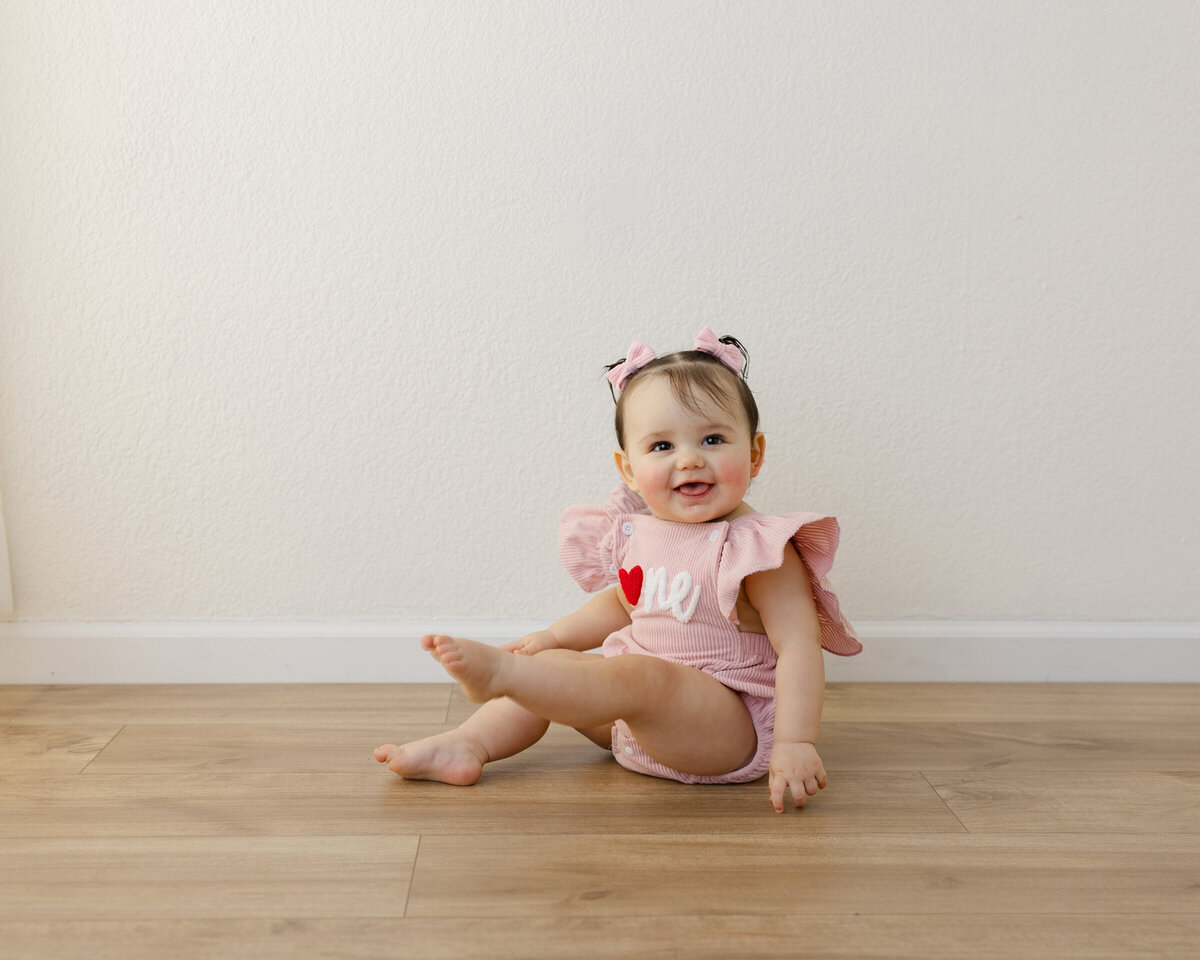 She wore her heart on her romper and her joy in every smile. Captured by Yucaipa cake smash photographer Kaitlyn Dawn Photography.