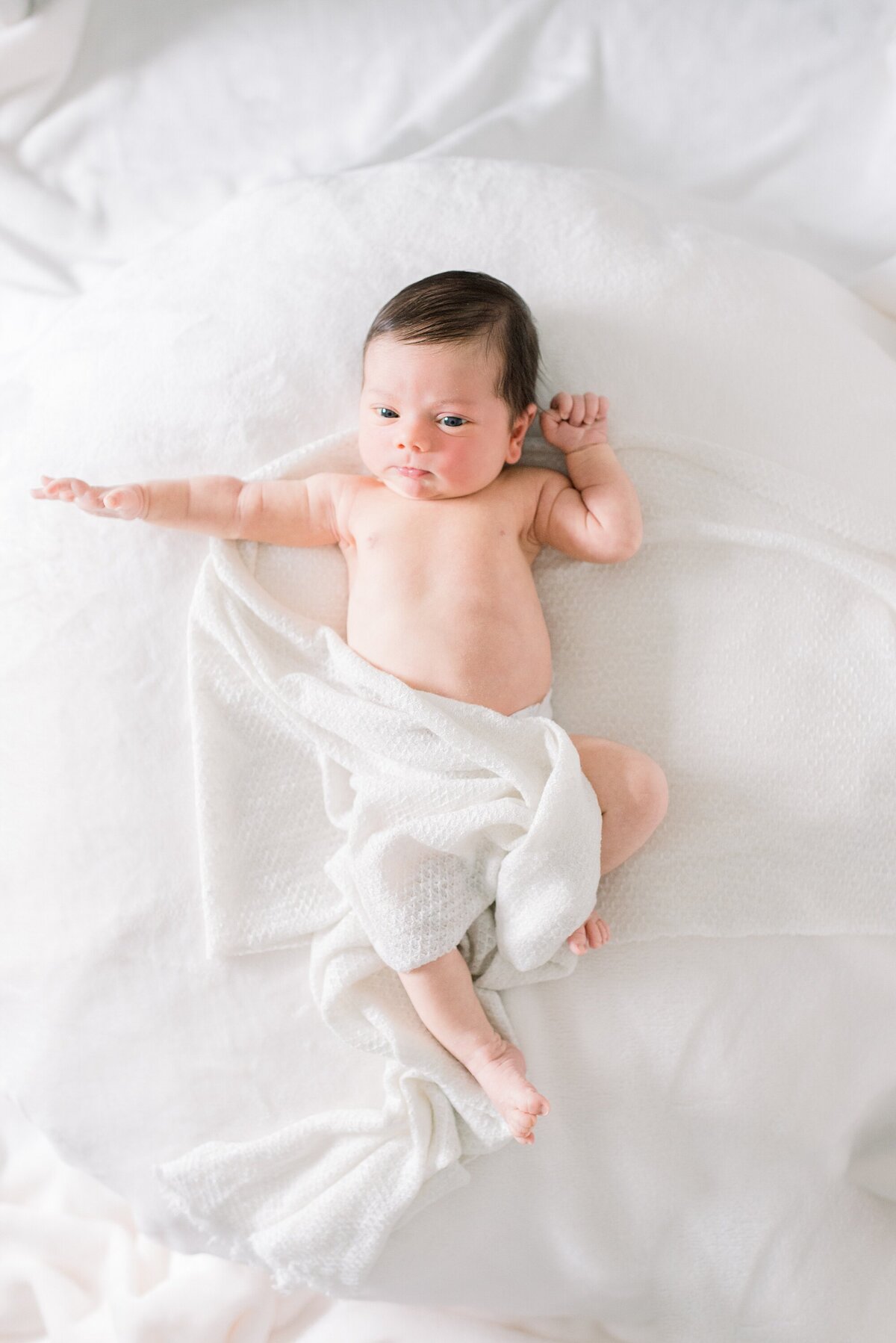 baby stretching in white swaddle by westchester newborn photographer nicole detone