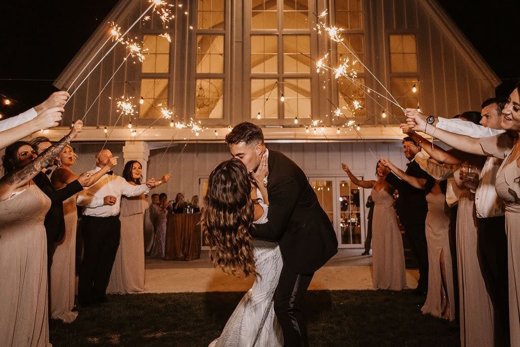 Groom dips his bride for a kiss as they make a sparkler exit after their wedding at Providence Vineyard