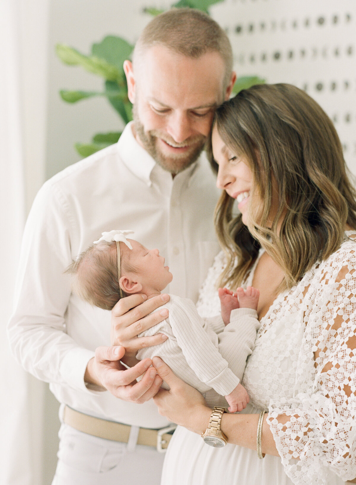Parents hold and admire their newborn daughter during their Raleigh newborn photography session. Photographed by Raleigh Newborn Photographer A.J. Dunlap Photography.