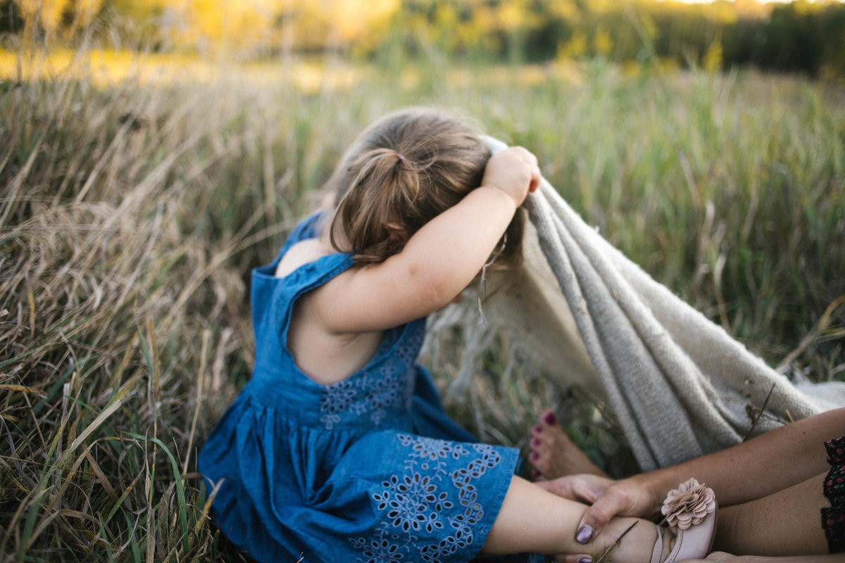 Little girl hiding under a blanket during photo session with Elle Baker Photography