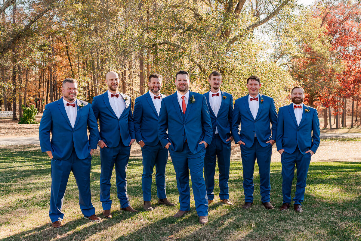 A groom with his six groomsmen in blue suits at Daniels Ridge during the fall sunset by JoLynn Photography, a Raleigh wedding photographer