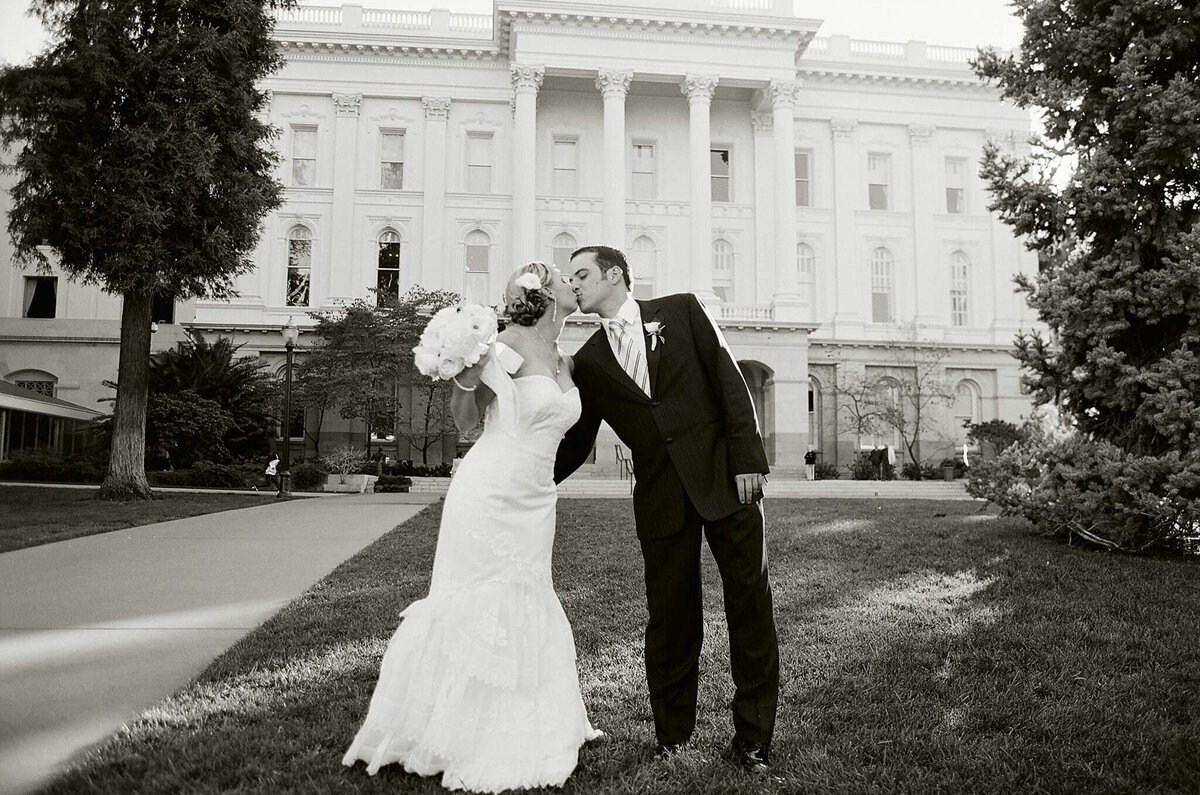 black and white film image of couple kissing in front of capitol building in sacramento, california