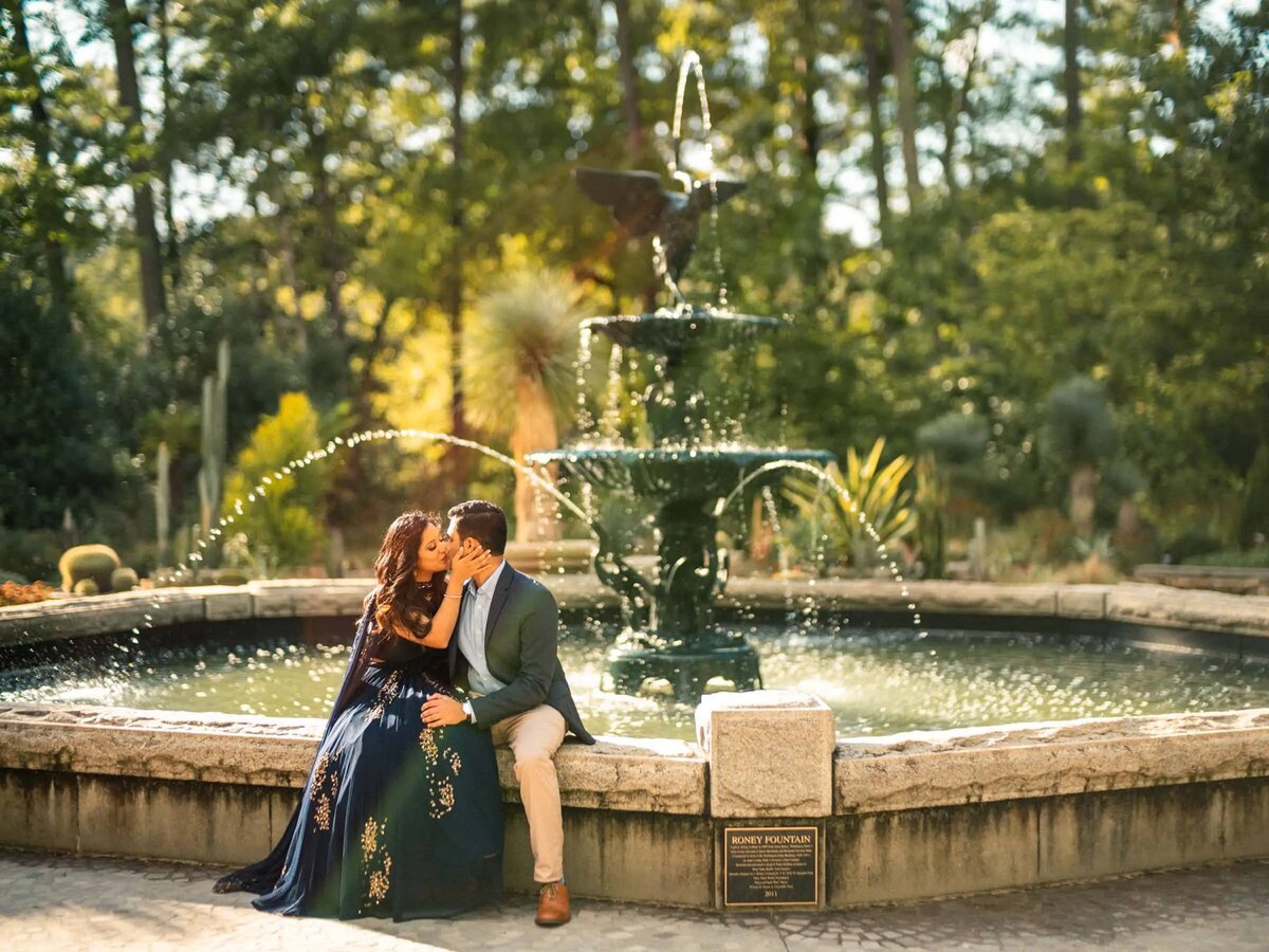 Couple seated closely by a fountain with water droplets frozen in time around them,