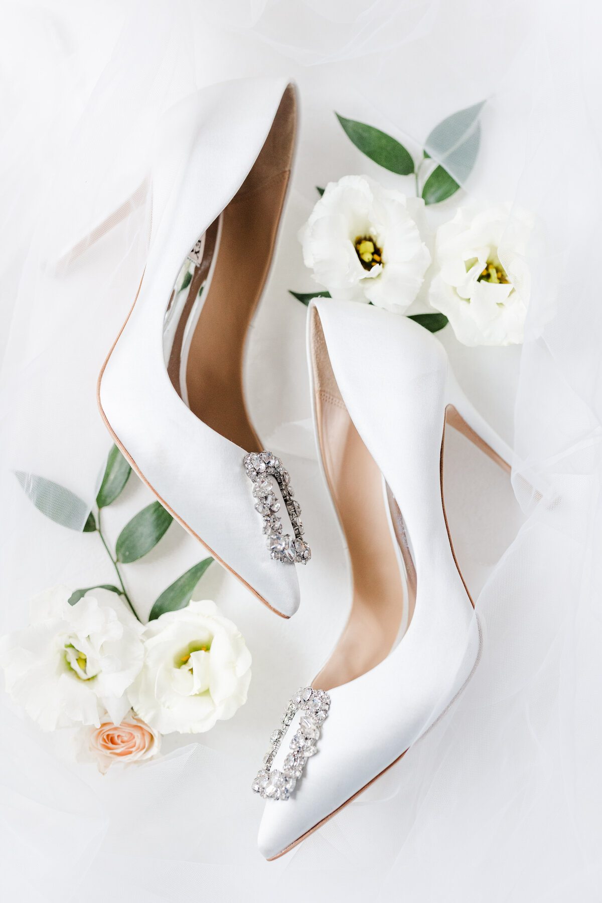 flat lay of white bridal shoes with white flowers