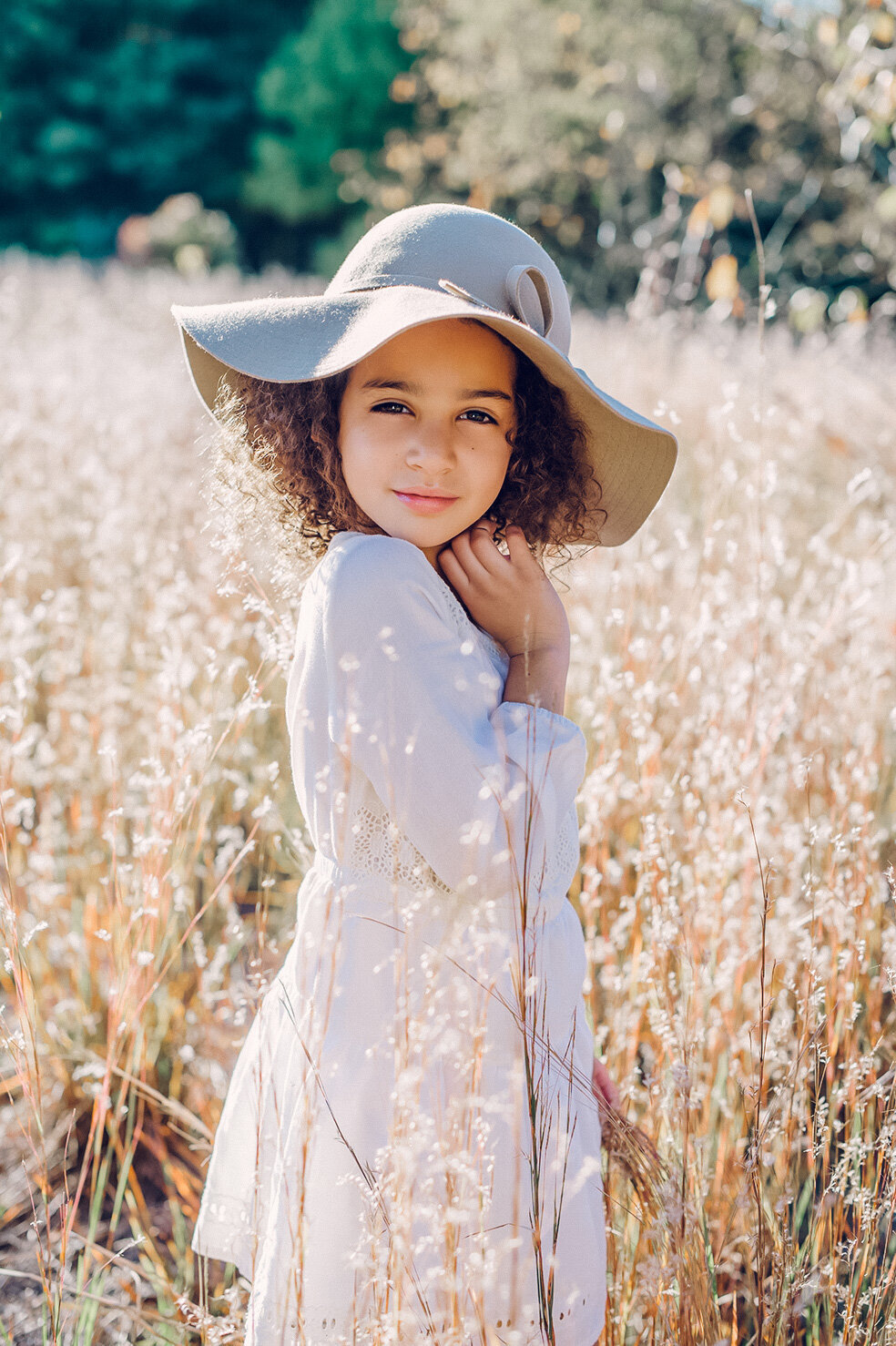 young girl in wheat field with hat in sunshine