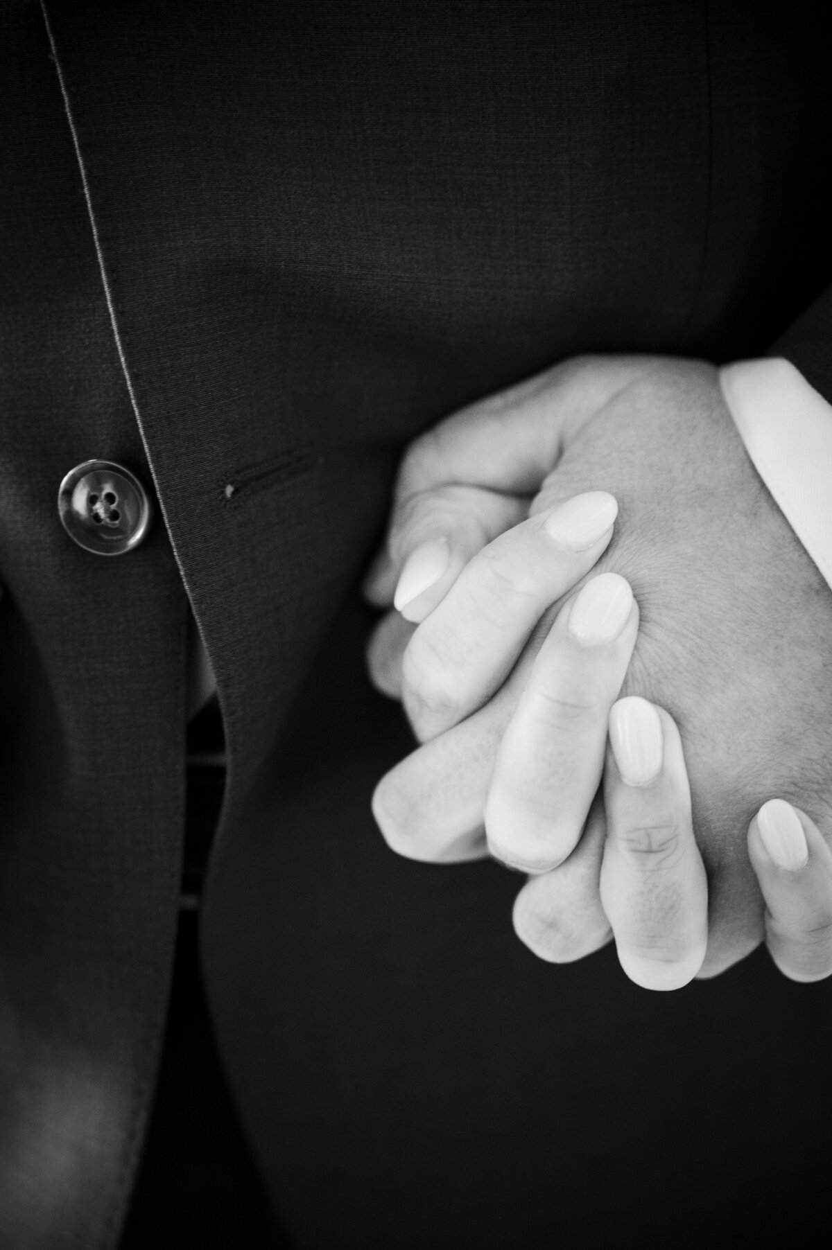 A close up shot of a bride and groom's hands intertwined.