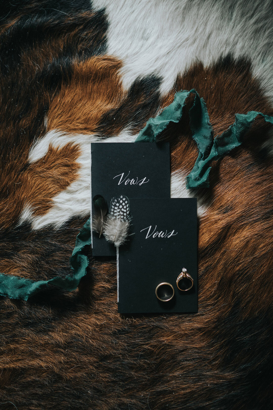 Black vow books with rings and a feather