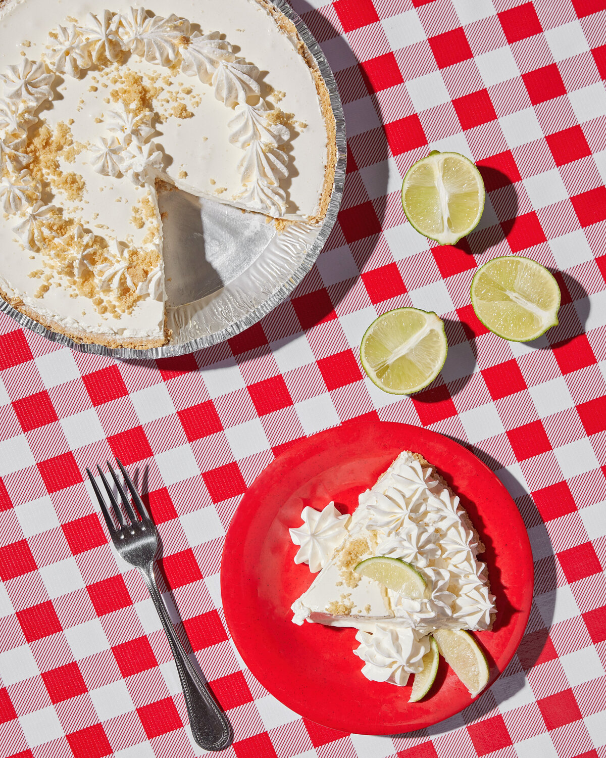 A key lime pie with a single piece on a red plate